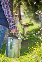 Woman leaving allotment carrying watering can