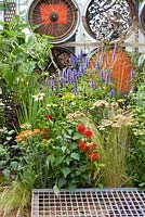 Metal grid and perennial border in contemporary garden; Echinacea 'Hot Papaya', Echinacea ' White Spider', Echinacea 'White Swan', Stipa tenuissima, Achillea 'Tarracotta', Agastache 'Blue Fortune'. 