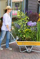 Woman pushing trolley of purchased plants, out of the garden centre