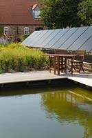 A solar panel installation in a garden setting next to waters edge - August, Summer 2014.