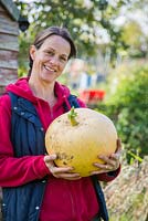 Proud woman holding harvested Pumpkin Hundred Weight. 