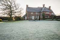 Frosty lawn in back garden of Elizabethan house, with bare shape of Liquidambar styraciflua 'Worplesdon' on the left. 