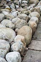 Large pebbles, packed tightly together, used as a mulch in a formal garden. 