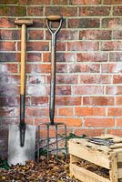 Vintage wooden fork and spade against a brick wall