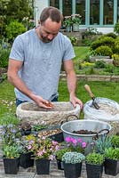 Practical step-by-step guide to planting a stone alpine trough with rock plants. All rock  plants need good drainage, so cover the drainage holes first with crocks - to prevent them becoming blocked and then cover with gravel to a depth of 2-3cm.