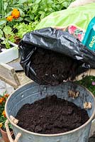 Planting a container herb garden. Step 2: fill the container with potting compost.