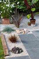 Completed gravel garden with black limestone paving and plants in Summer.
