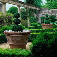 At Iford Manor, the formal Casita garden is defined with box hedges and topiary shapes in huge old stone pots. A gnarled Wisteria sinensis clambers up a stone colonnade.