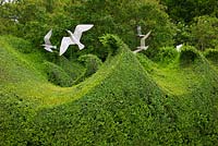 Clipped topiary hedge of Buxus sempervirens in the shape of waves with sculptural seagulls by Diane Maclean at Farleigh House, Hampshire