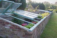 Restored cold frames containing plants for sale. Littlebredy Walled Gardens, Dorset