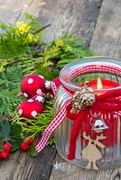Red polkadot baubles beside a glass candle holder, with Cedar and Skimmia foliage