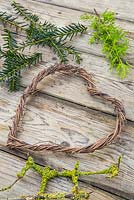 Twined heart wreath made from vines, with foliage of Conifer and Prunus with lichen