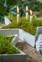 Display of white stars planted with moss and candles, accompanied with Pine cones and mixed evergreen foliage