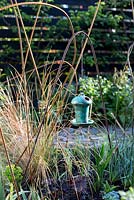 Decorative ceramic bird box suspended on building rail plant support in  town garden, Brixton