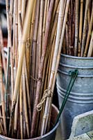 Bamboo canes stored in galvanised metal buckets in town garden, Brixton