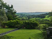 The view over rill and purple wisteria in Burrow Farm Millenium garden to Axe Valley in the distance.