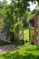 Entrance to walled garden with wrought iron gates and fallen apples. The Tithe Barn, Cerne Abbas, Dorset