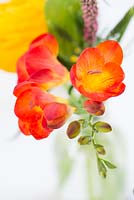 Close up of a cut flower arrangement with orange freesias