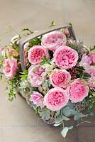 Pink roses in an arrangement in a basket. Rose 'Rosalind' and 'Miranda' cut flower rose varieties from David Austin Roses