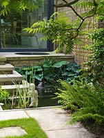 A bubbling, circular pool on the terrace feeds a rectangular pool below, edged in hosta, iris and fern and beneath a sumach.
