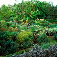 Dragon Garden. Central pool reflects Miscanthus sinensis 'Roland', Positano and Juli. Sedum telephium 'Matrona', Pennisetum villosum, phormium and calamagrostis.