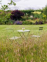 Table and chairs in natural meadow of grasses and wildflowers