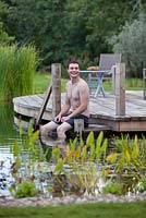Man relaxing by a swimming pond.