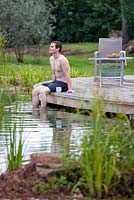 Man relaxing by swimming pond.