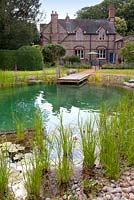 View of a house and natural swimming pond. July. 