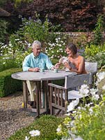 John and Kate Bolsover relax in the cottage garden parterre, along with their dog, Washington.