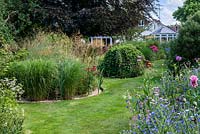 A grass path leading to the house through double borders planted with Calamagrostis, Miscanthus, Stipa grasses and annual wildflower mix.