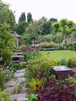 Riverside garden by Andy Sturgeon. Path leads past cotinus, euphorbia, libertia, carex. Oak cubes pass allium, erysimum, Hebe vernicosa, box, iris, aquilegia, fern.