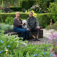 Sandy and Penny Burnfield with Sammy, their West Highland terrier, sit on a retaining wall in front of their part C19 cottage overlooking the River Test valley.