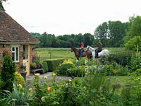 Owner Sandy Burnfield on horseback, accompanied by Sarah Johns, outside his country garden overlooking the River Test valley.