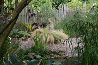 A gravel garden with Stipa grasses surrounding a stone statue.