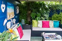 A covered seating area with seaside inspired decorations, sofa and table.