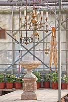 Umbrellas, chandeliers, and bell hanging in the glasshouse. Helleborus showed on shelves.