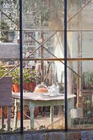 Glasshouse windows. Teapot and self baked apple pie covered on wooden table.