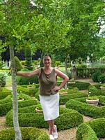 Trudie Proctor in the 6-year-old parterre of low, rounded box hedges, offset against gravel. Within, there are standard hollies and pots of white geraniums.