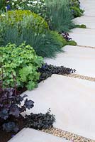 The Time In Between by Husqvarna and Gardena.  Wide paving edged with Alchemilla mollis, Ajuga reptans, Heuchera and Festuca 
