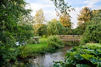 Wooden bridge across stream in country garden.