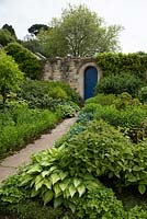 Pathway leading to doorway in stone wall at Kiftsgate Court Gardens, Chipping Campden, Gloucestershire,UK