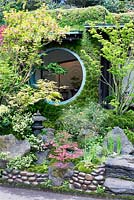 Edo no Niwa - Edo Garden.  View of the house with wall covered by  Leucobryum juniperoideum and old bonsai in a circural window,  surrounded by Pinus, Enkianthus campanulatus and Acer palmatum 'Little Princess' - RHS Chelsea Flower Show, 2015