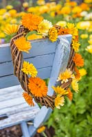 Woven heart wreath decorated with Calendula officinalis 'Art Shades' flowers
