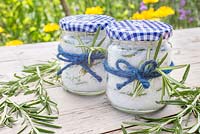 Homemade rosemary salt, made using sea salt and leaves of Rosmarinus officinalis, in glass jars, tied with string