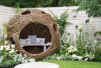 Spherical willow bird hide with bench, white flower borders with white painted fencing and bird houses - Living Landscapes: City Twitchers Garden, RHS Hampton Court Palace Flower Show 2015