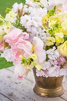 Floral display of Cheiranthus cheiri 'Ivory White', Tulipa 'Creme Lizard', Tulip 'Sunny Prince', Tulip 'Apricot Beauty' and Cherry Blossom in bronze bucket