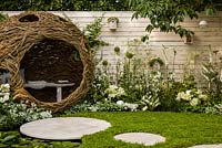 Living Landscapes 'City Twitchers' - view showing circular paved areas, camomile lawn, pond, spherical willow bird hide, nesting boxes and mixed planting in whites - RHS Hampton Court Flower Show 2015