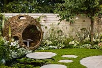 Living Landscapes 'City Twitchers' - view showing circular paved areas, camomile lawn, pond, spherical willow bird hide, nesting boxes, prunus tree and mixed white planting - RHS Hampton Court Flower Show 2015