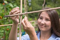 Secure a garden cane horizontally to the vertical canes using string or twine